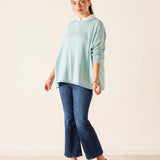 Woman wearing a light blue sweater and dark blue jeans against a white background