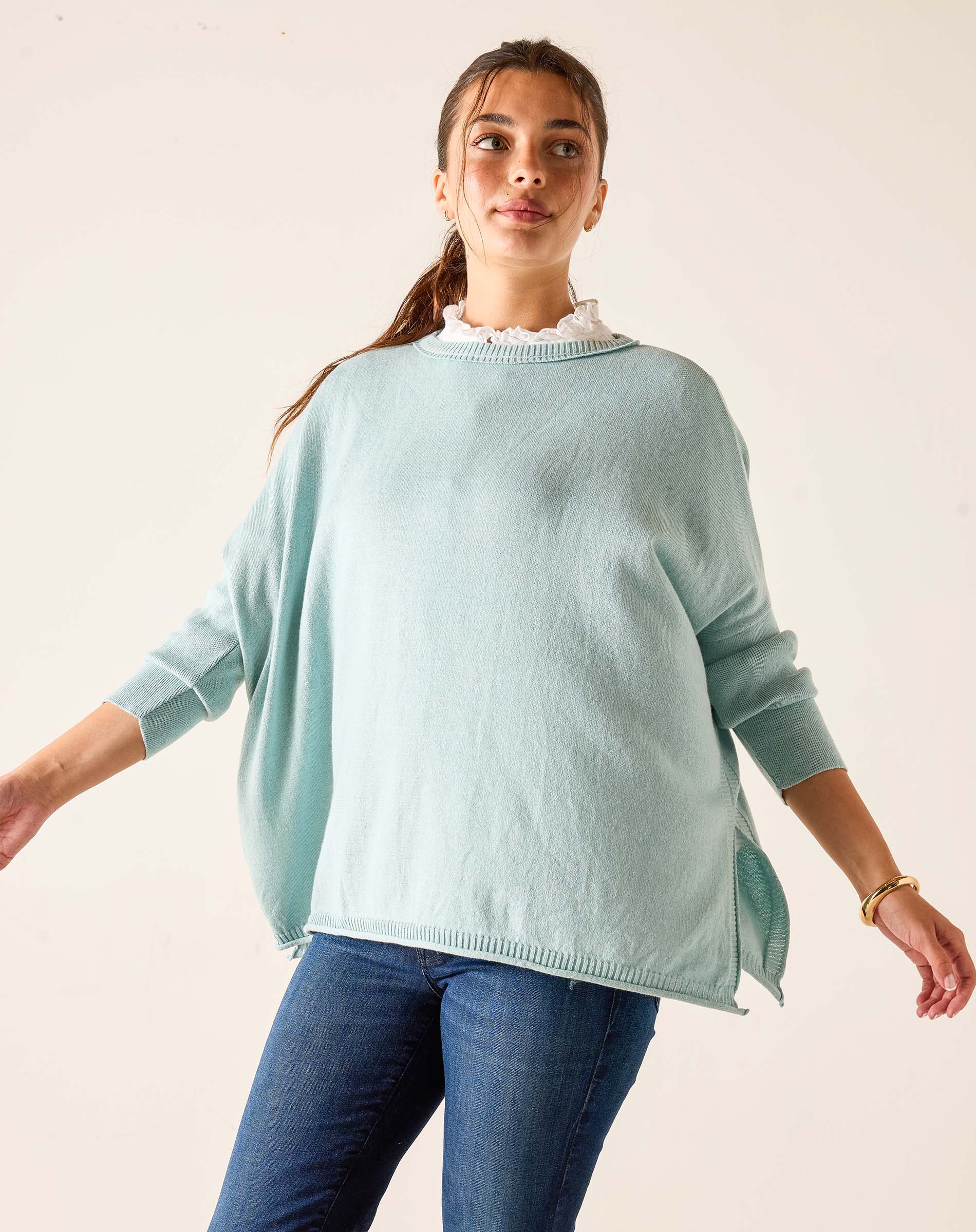 Woman wearing a light blue sweater and blue jeans against a plain background