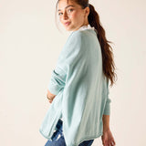 Woman wearing a light blue sweater and jeans against a plain background