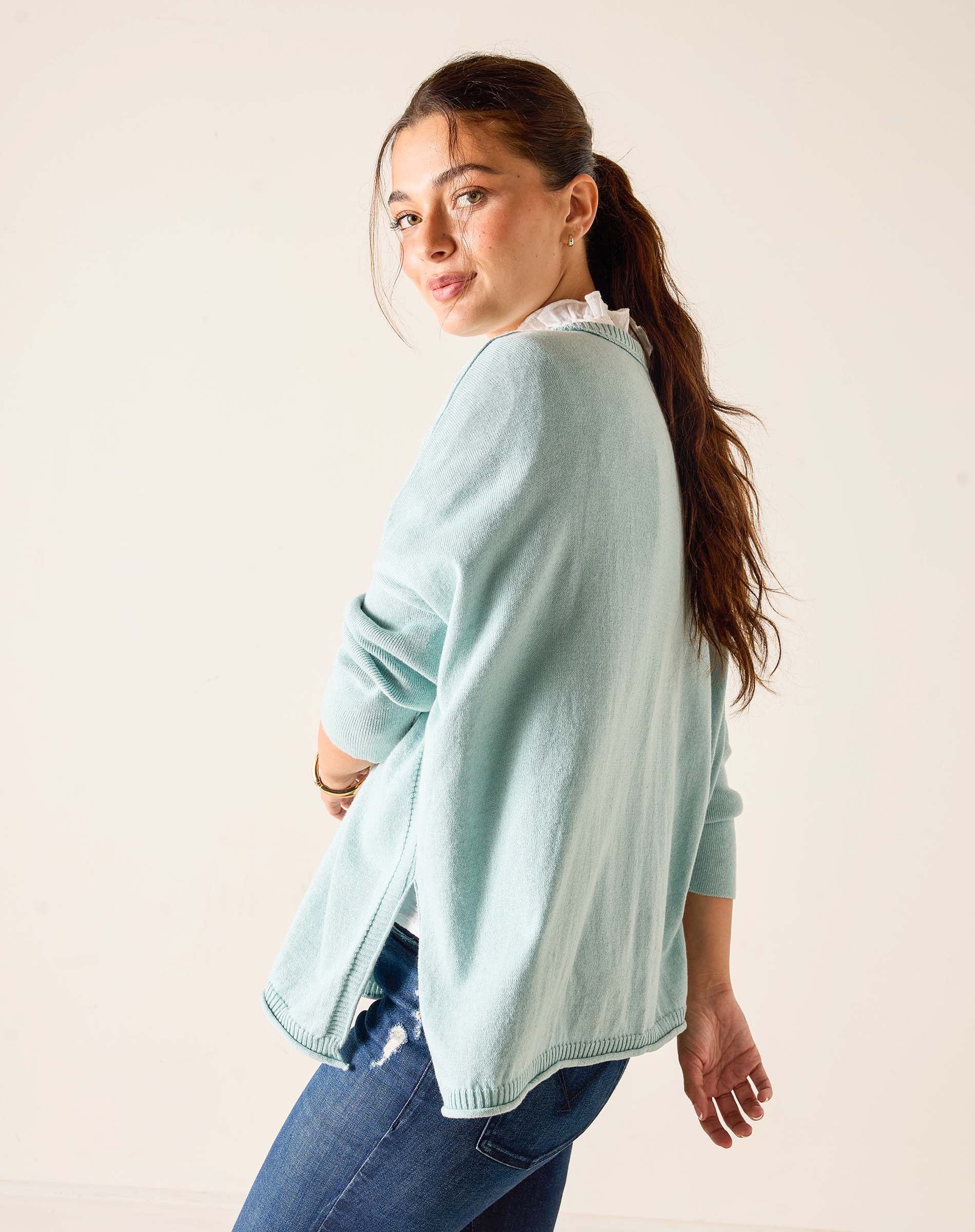 Woman wearing a light blue sweater and jeans against a plain background