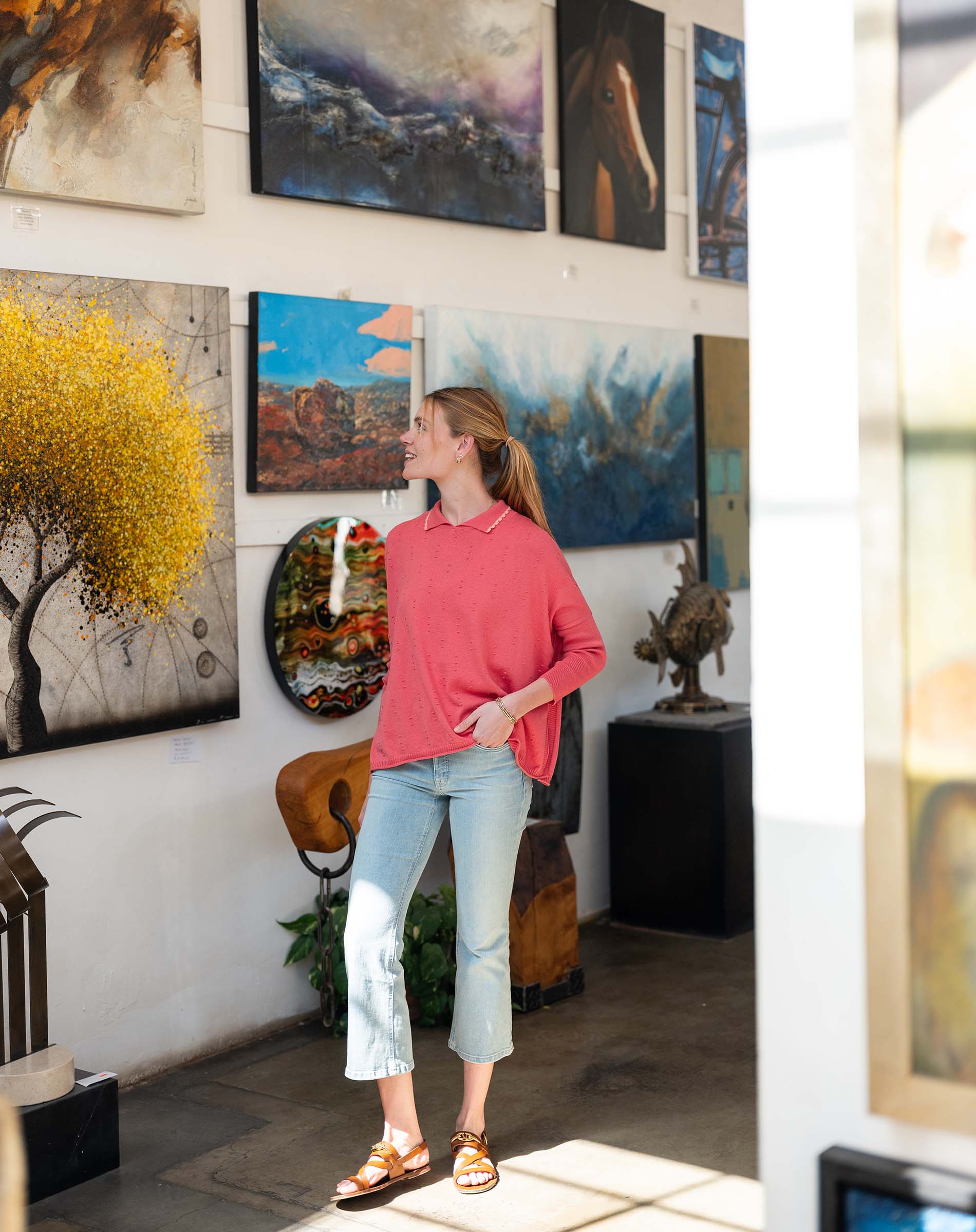 Woman standing in an art gallery surrounded by various paintings.