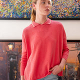 Woman wearing a pink sweater standing in front of a colorful abstract painting