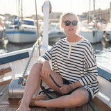 Woman sitting on a boat deck with yachts in the background