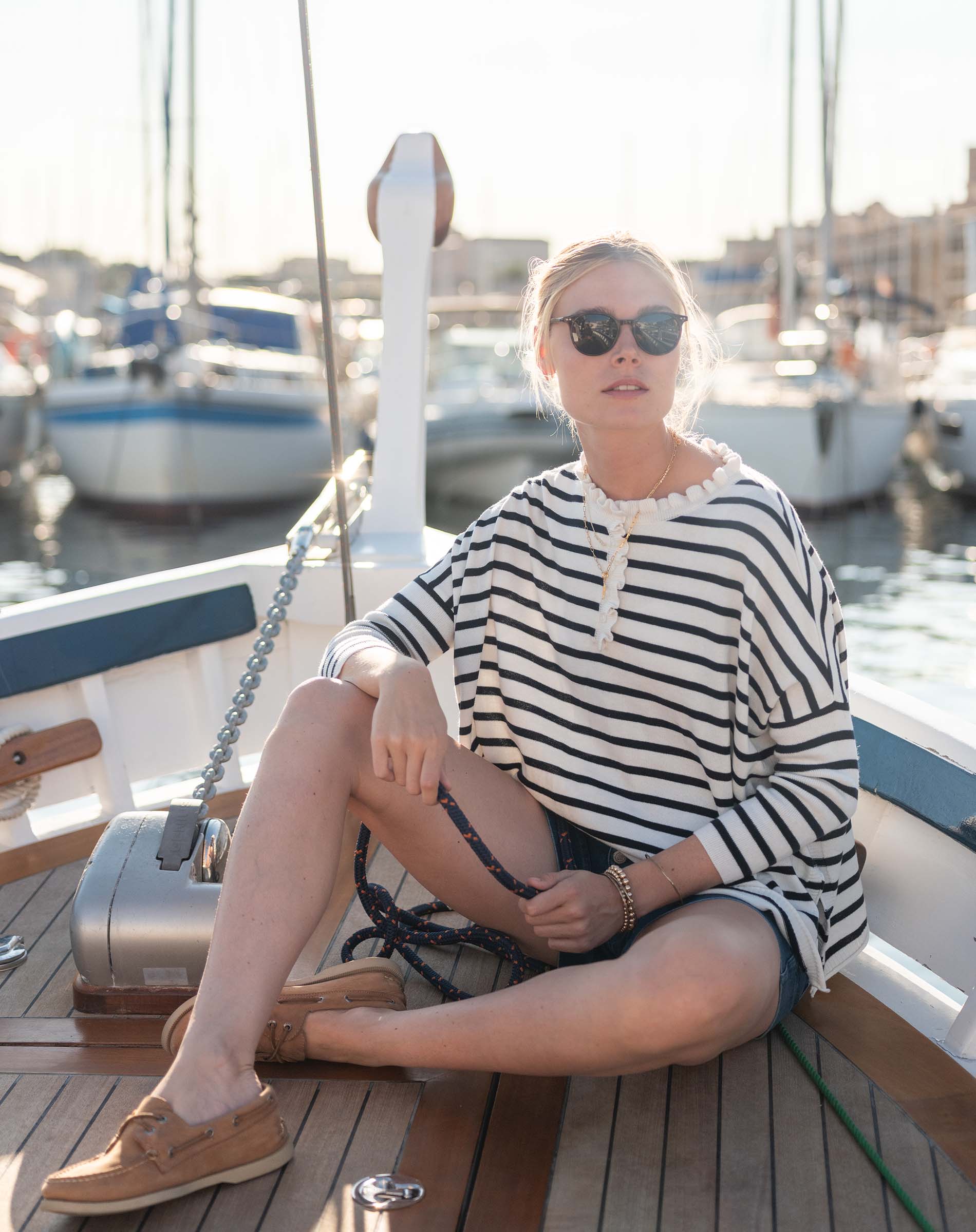 Woman sitting on a boat deck with yachts in the background