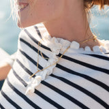 Woman wearing a black and white striped shirt with a necklace featuring a large white stone.