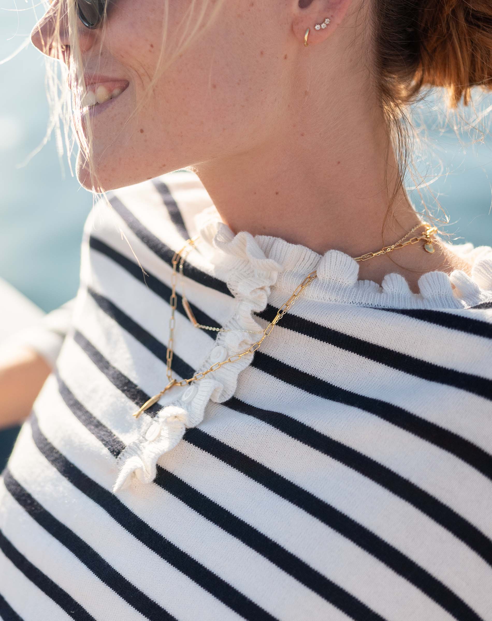 Woman wearing a black and white striped shirt with a necklace featuring a large white stone.