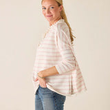 Woman wearing a light pink striped shirt and blue jeans against a plain background