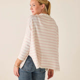 Woman wearing a striped sweater and jeans against a plain background