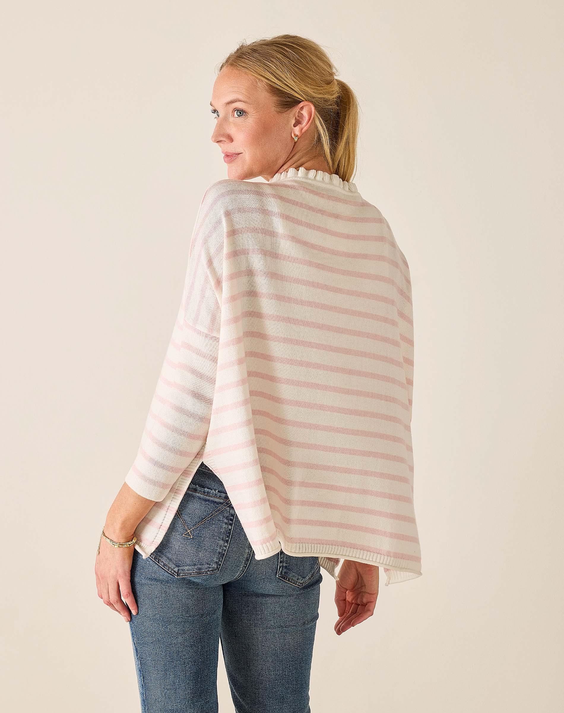 Woman wearing a striped sweater and jeans against a plain background