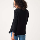 Person wearing a black long-sleeve top and blue jeans on a white background