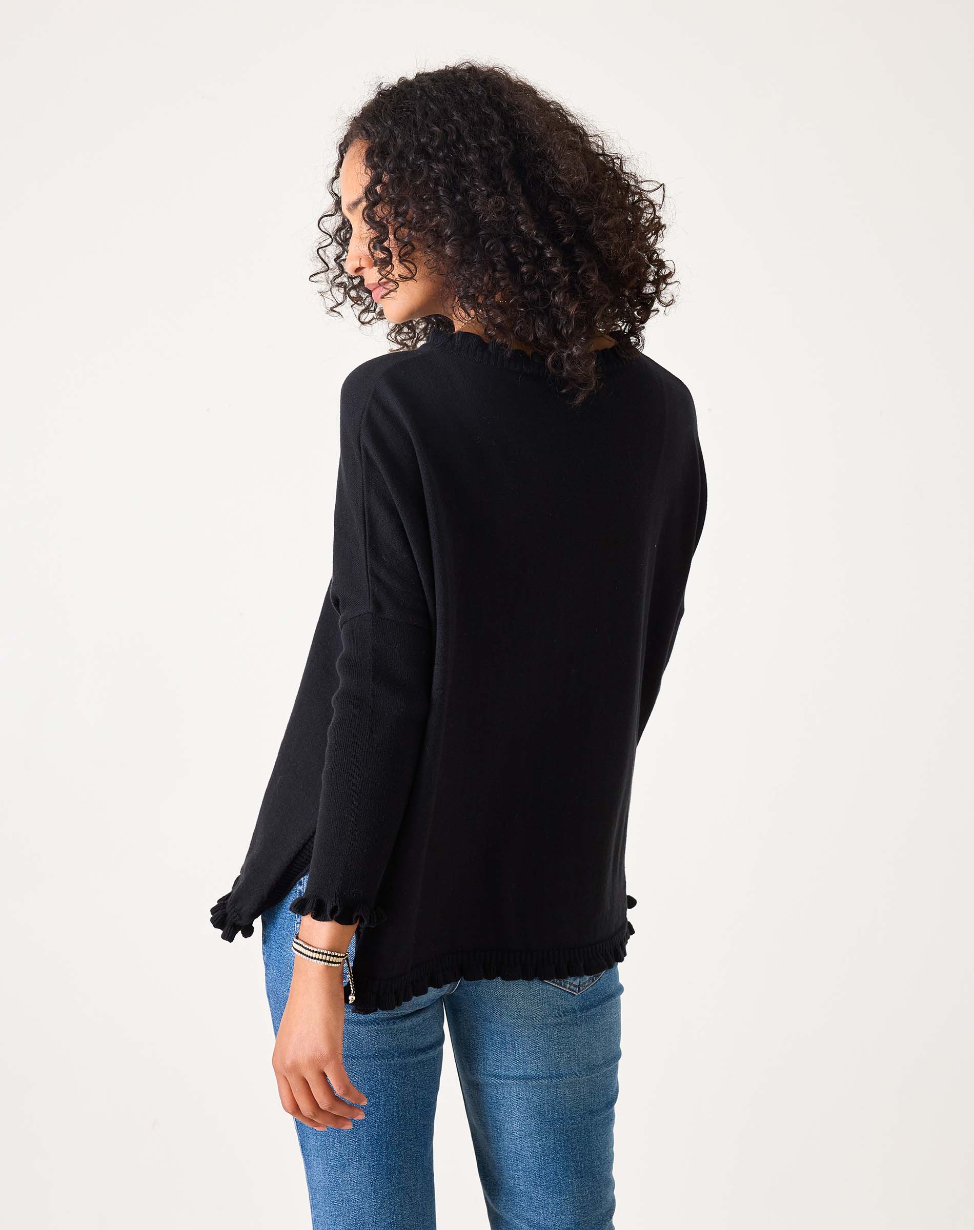 Person wearing a black long-sleeve top and blue jeans on a white background