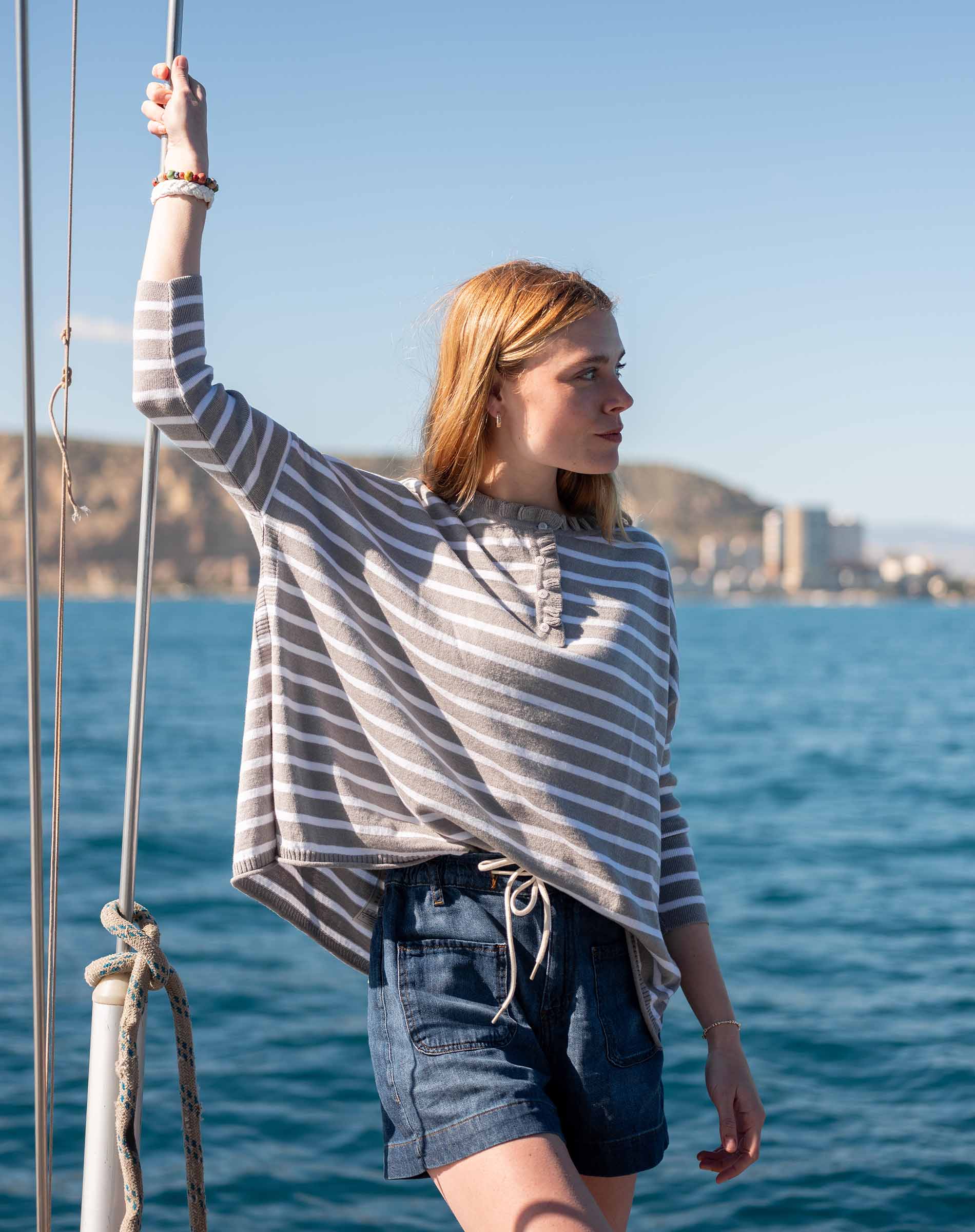 MERSEA women's travel-friendly grey striped ruffled henley top in a beach setting.