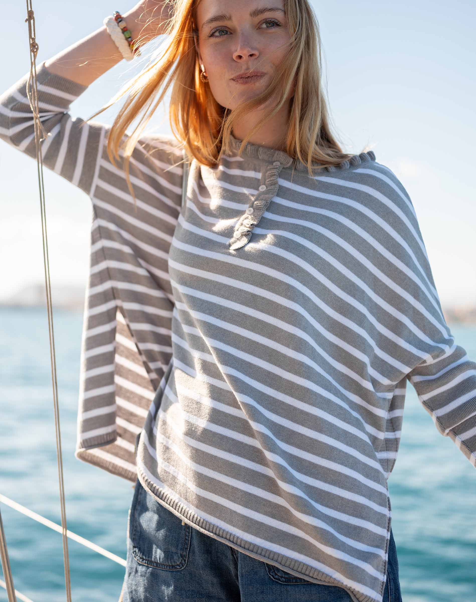 Grey striped cotton ruffle henley top worn on a boat at sea.