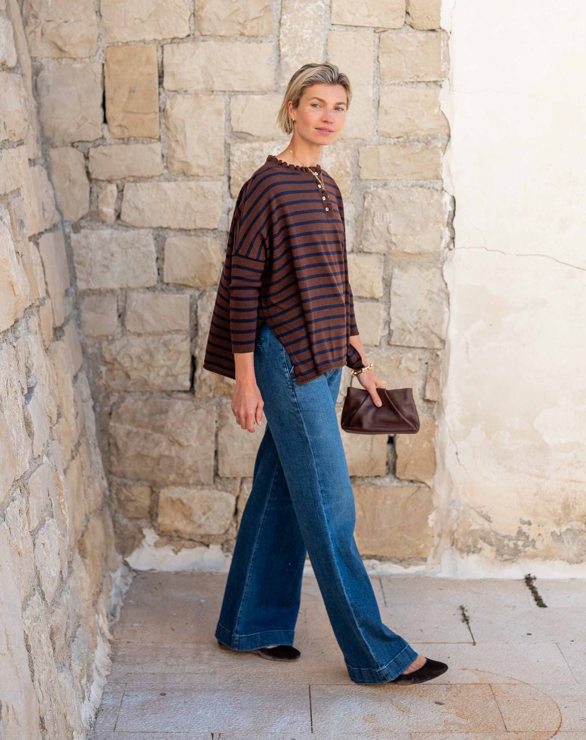 Walnut and marine striped ruffle henley in cotton; paired with wide-leg denim jeans.