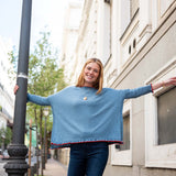 Aegan blue cotton ruffle sweater with red trim and gold button details.