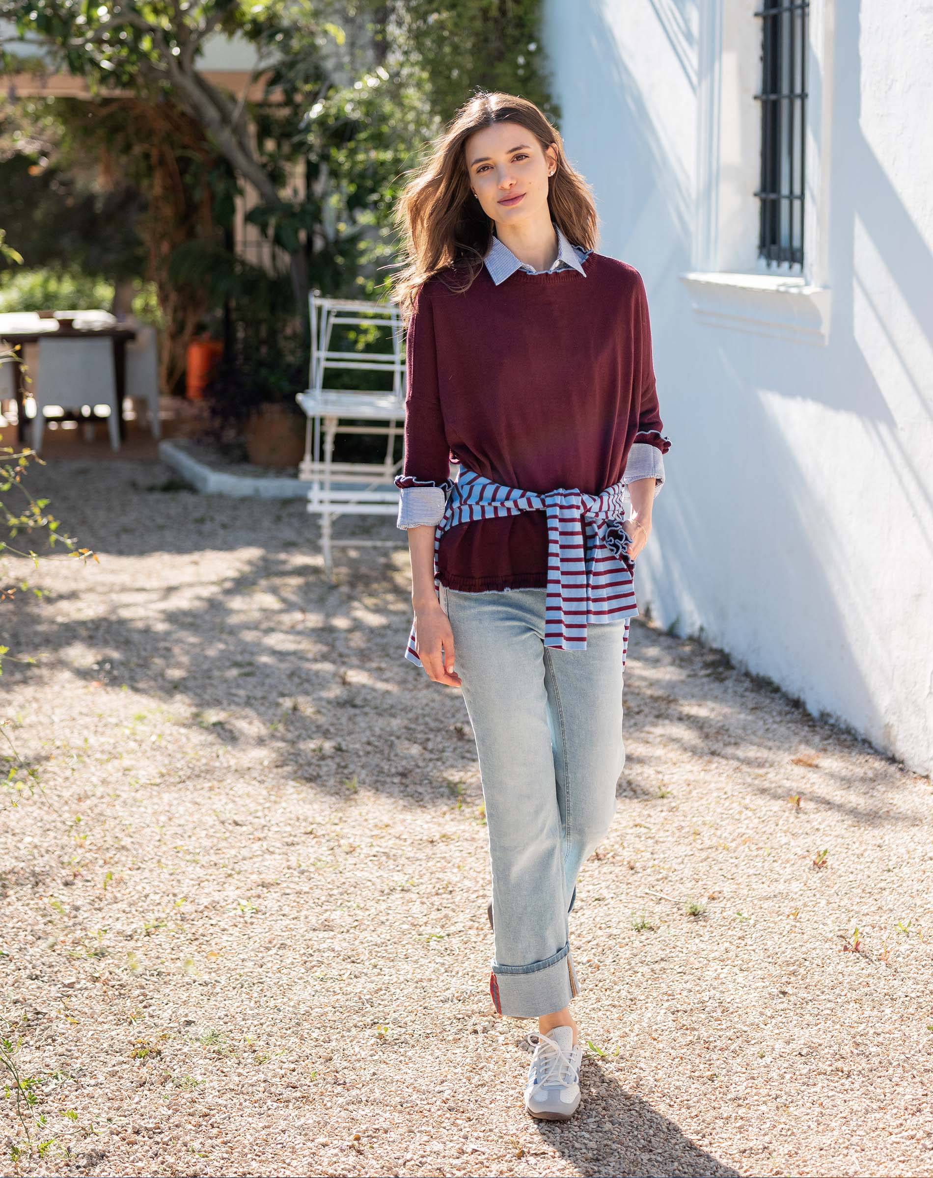 MERSEA women's travel-friendly burgundy and sapphire blue striped ruffle sweater with a buttoned collar, worn over denim jeans.