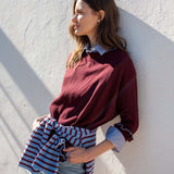 Burgundy cotton ruffle sweater with a striped wrap tied around the waist.
