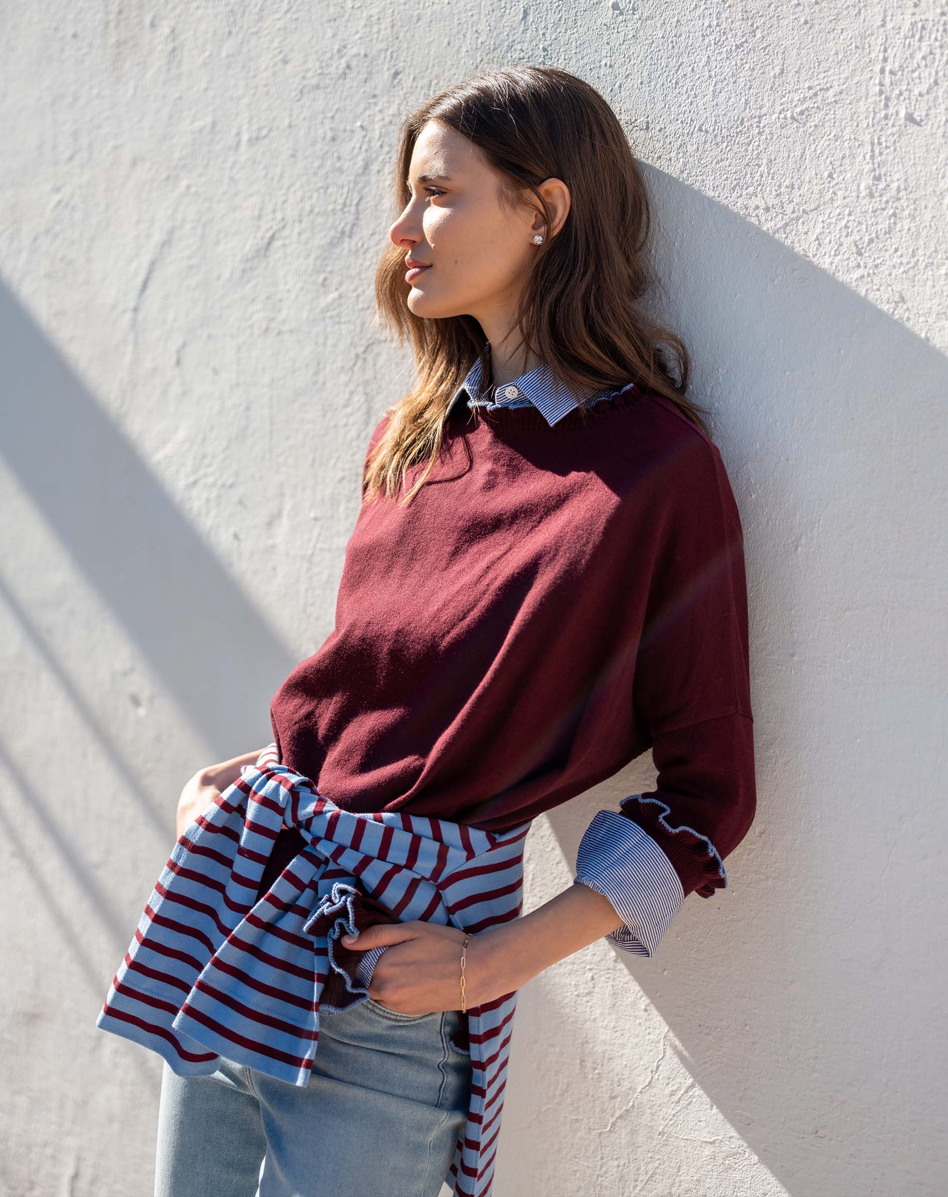 Burgundy cotton ruffle sweater with a striped wrap tied around the waist.