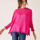 Woman wearing a bright pink sweater with ruffled cuffs and hem on a plain background