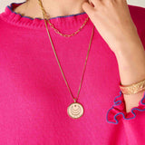 Person wearing a gold necklace with a pink top