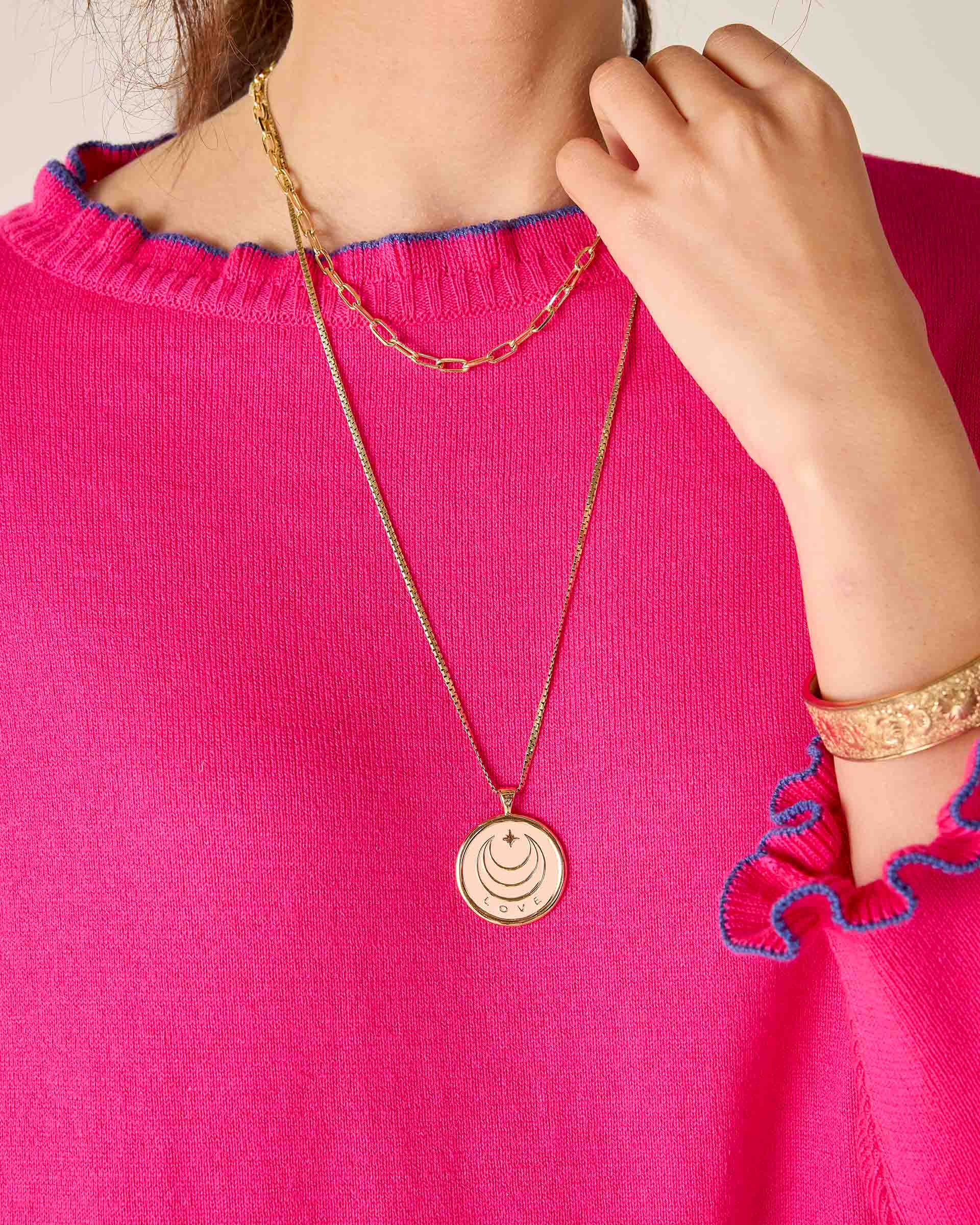 Person wearing a gold necklace with a pink top
