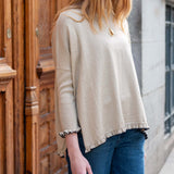Natural beige knit sweater with ruffled hem and cuffs.