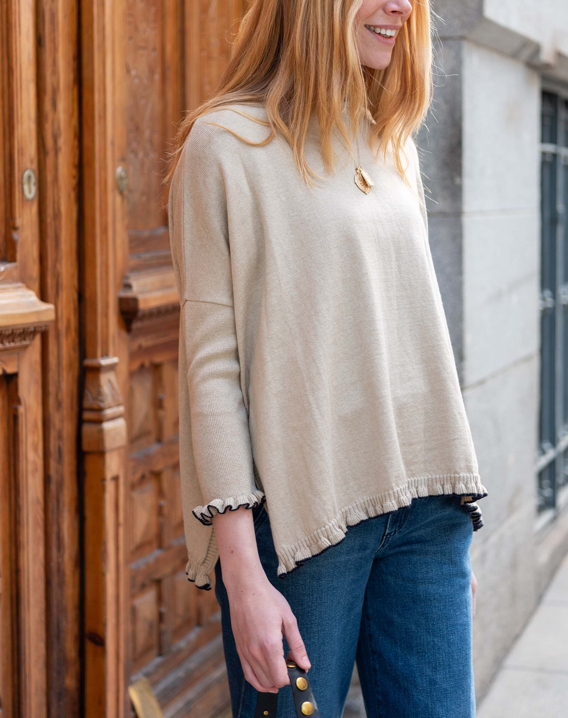Natural beige knit sweater with ruffled hem and cuffs.