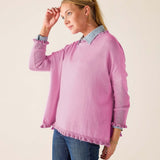 Woman wearing a pink blouse with rolled-up sleeves and blue jeans on a beige background