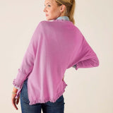 Woman wearing a pink sweater and blue jeans against a plain background