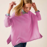 Woman wearing a pink sweater with ruffled trim on a beige background