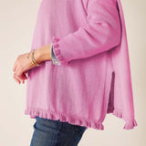 Person wearing a pink sweater and blue jeans on a beige background