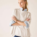 Warm white cotton ruffle sweater with a ruffled hem and layered light blue shirt underneath.