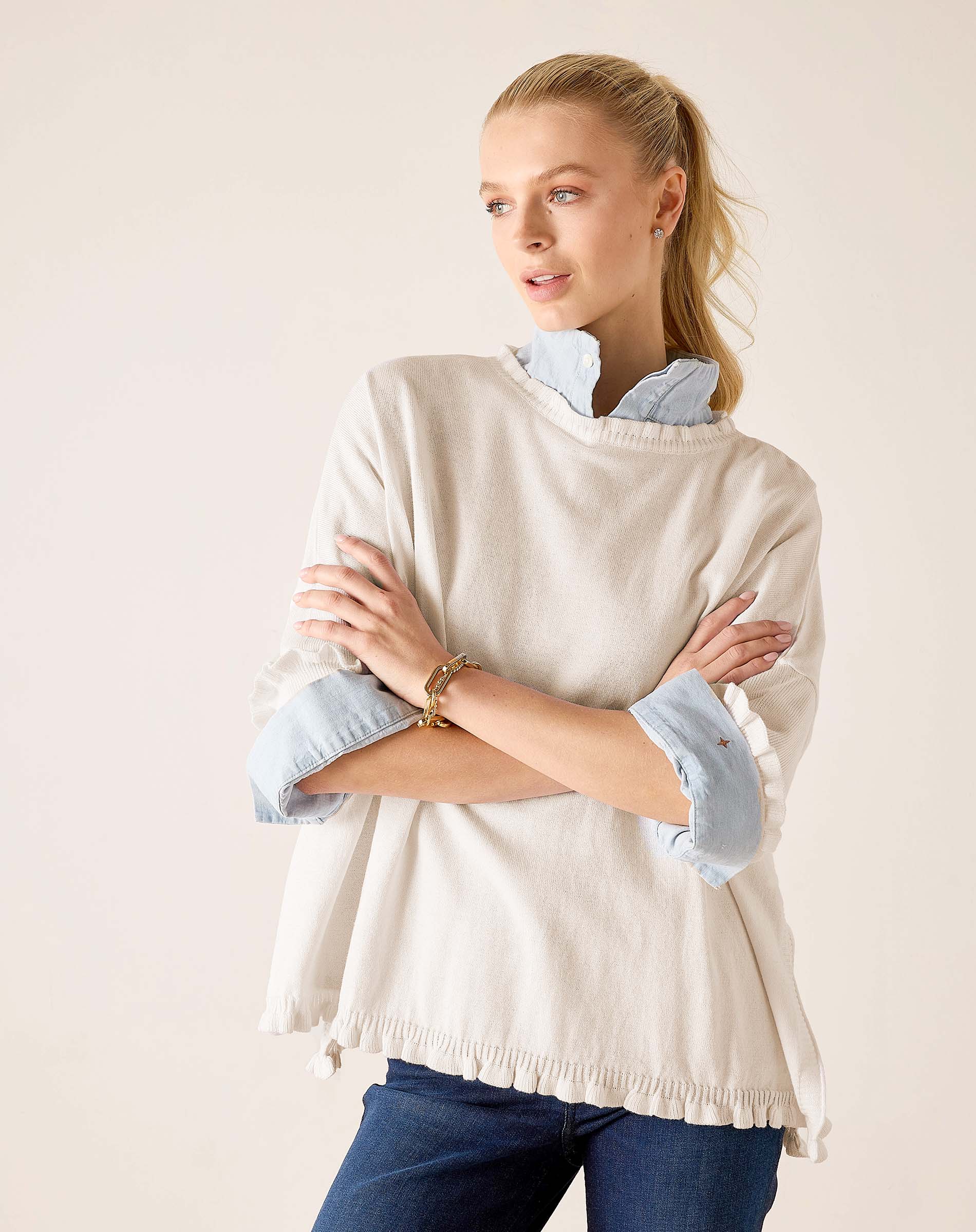 Warm white cotton ruffle sweater with a ruffled hem and layered light blue shirt underneath.