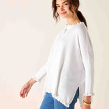 Woman wearing a white blouse and blue jeans against a plain background