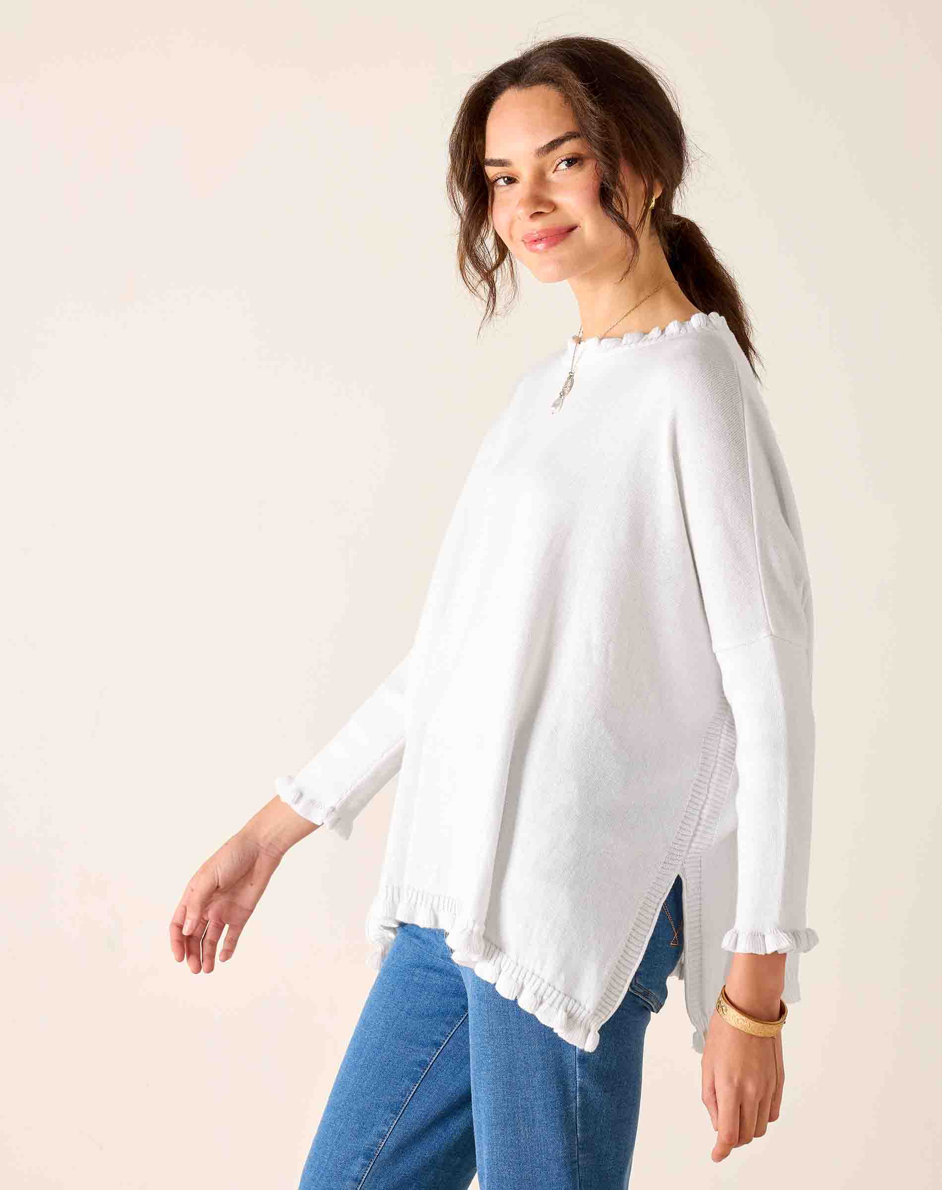 Woman wearing a white blouse and blue jeans against a plain background