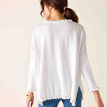 Woman wearing a white long-sleeve top with a subtle pattern on a beige background