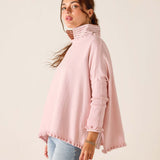 Woman wearing a pink turtleneck sweater against a plain background