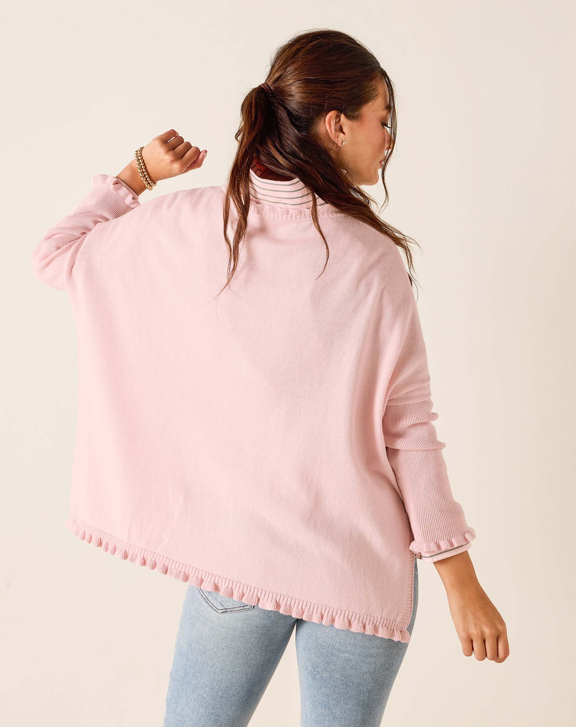 Person wearing a pink sweater with a white background