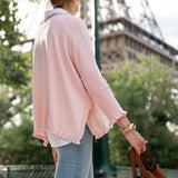 Person wearing a pink cardigan and holding a brown bag with the Eiffel Tower in the background