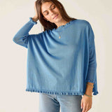 Woman wearing a blue sweater and jeans against a plain background