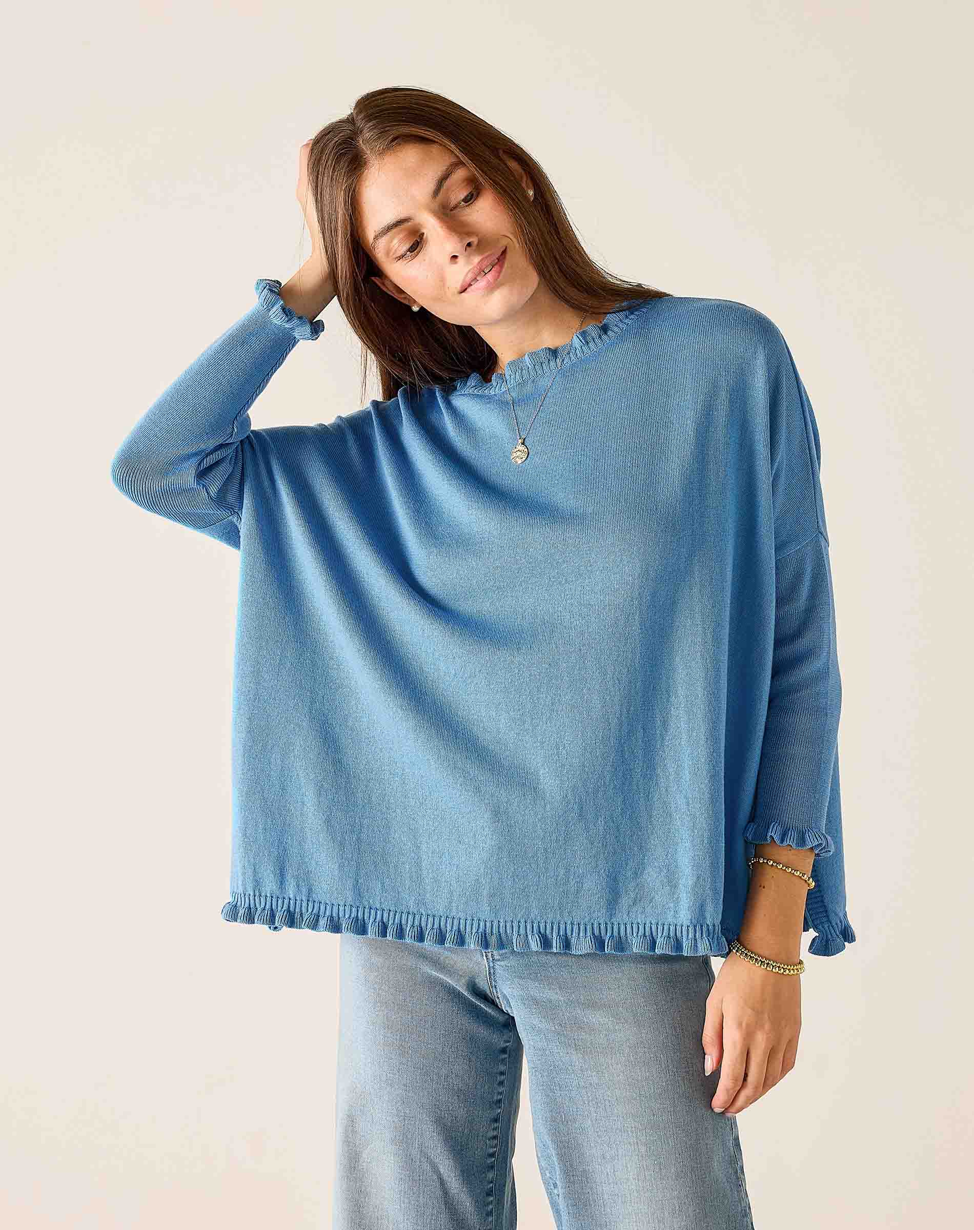 Woman wearing a blue sweater and jeans against a plain background
