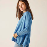 Woman wearing a blue sweater and jeans against a plain background