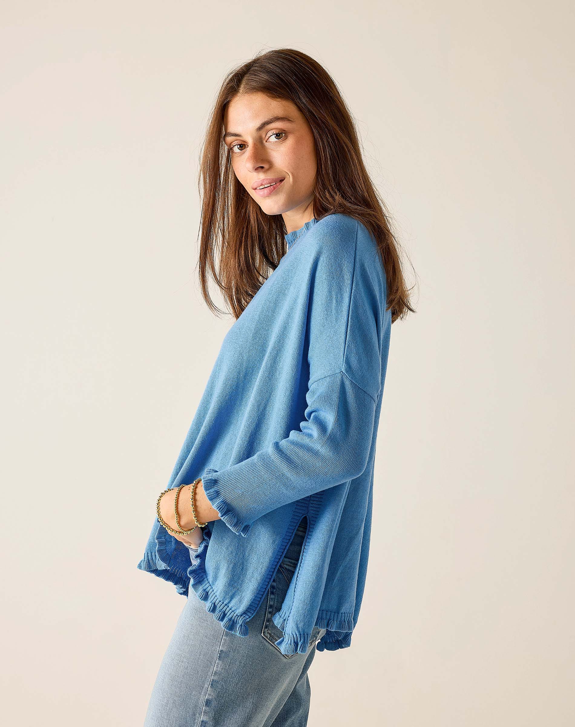 Woman wearing a blue sweater and jeans against a plain background