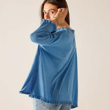 Woman wearing a blue sweater and jeans against a plain background