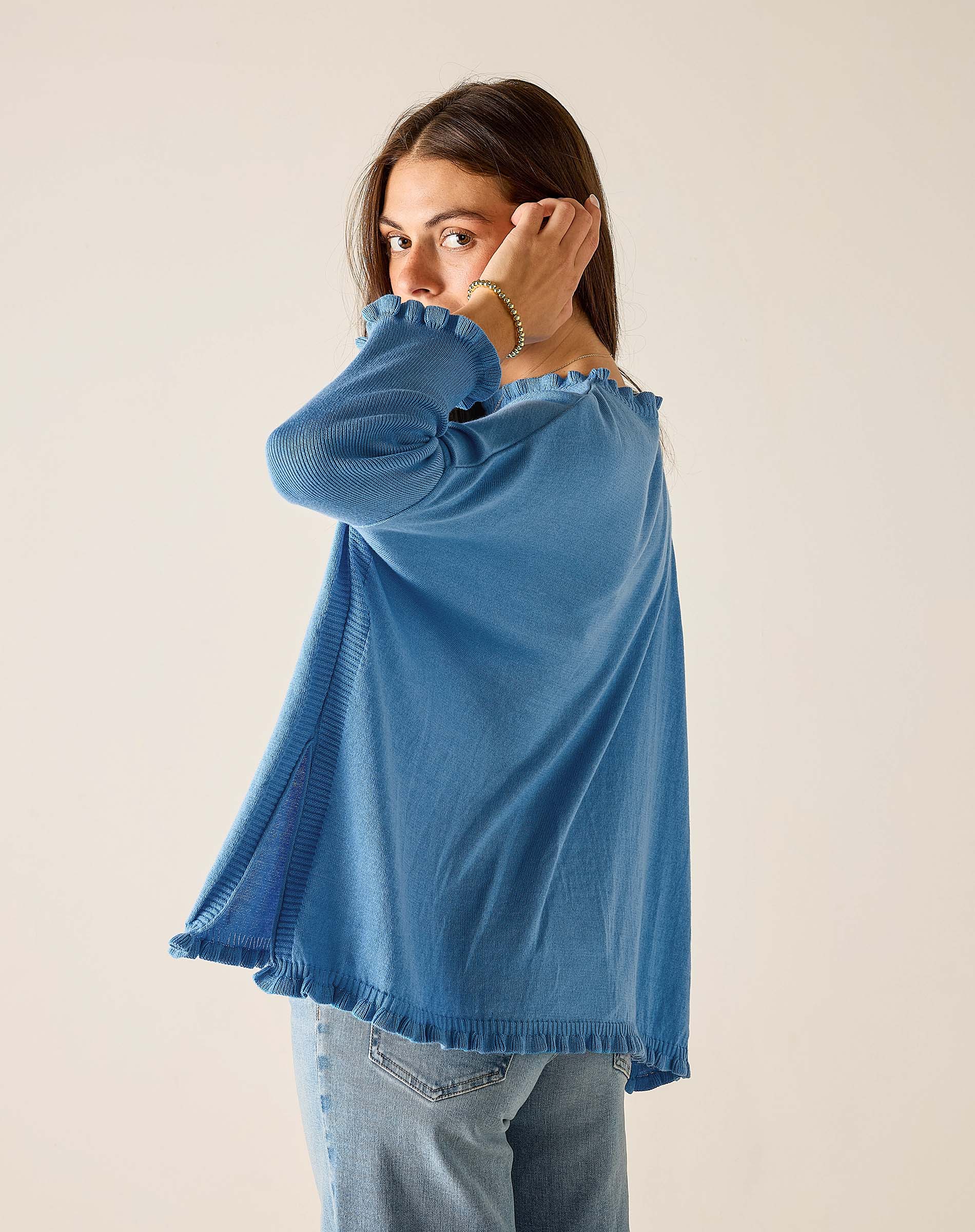 Woman wearing a blue sweater and jeans against a plain background