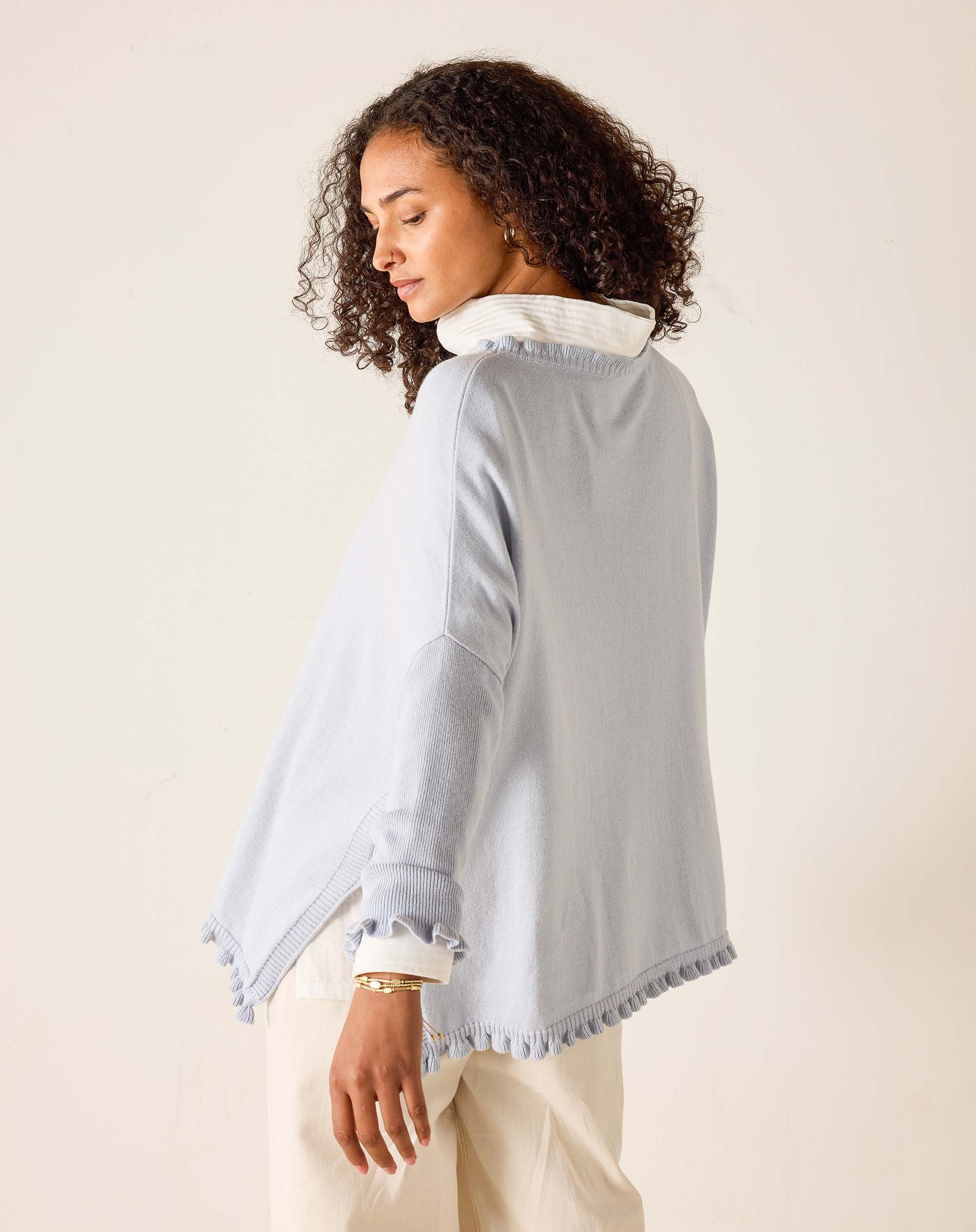 Woman wearing a light blue jacket with white trim on a beige background