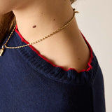 Close-up of a person wearing a gold necklace with a plain background