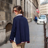 Woman walking down a city street wearing a navy blue jacket and beige pants.