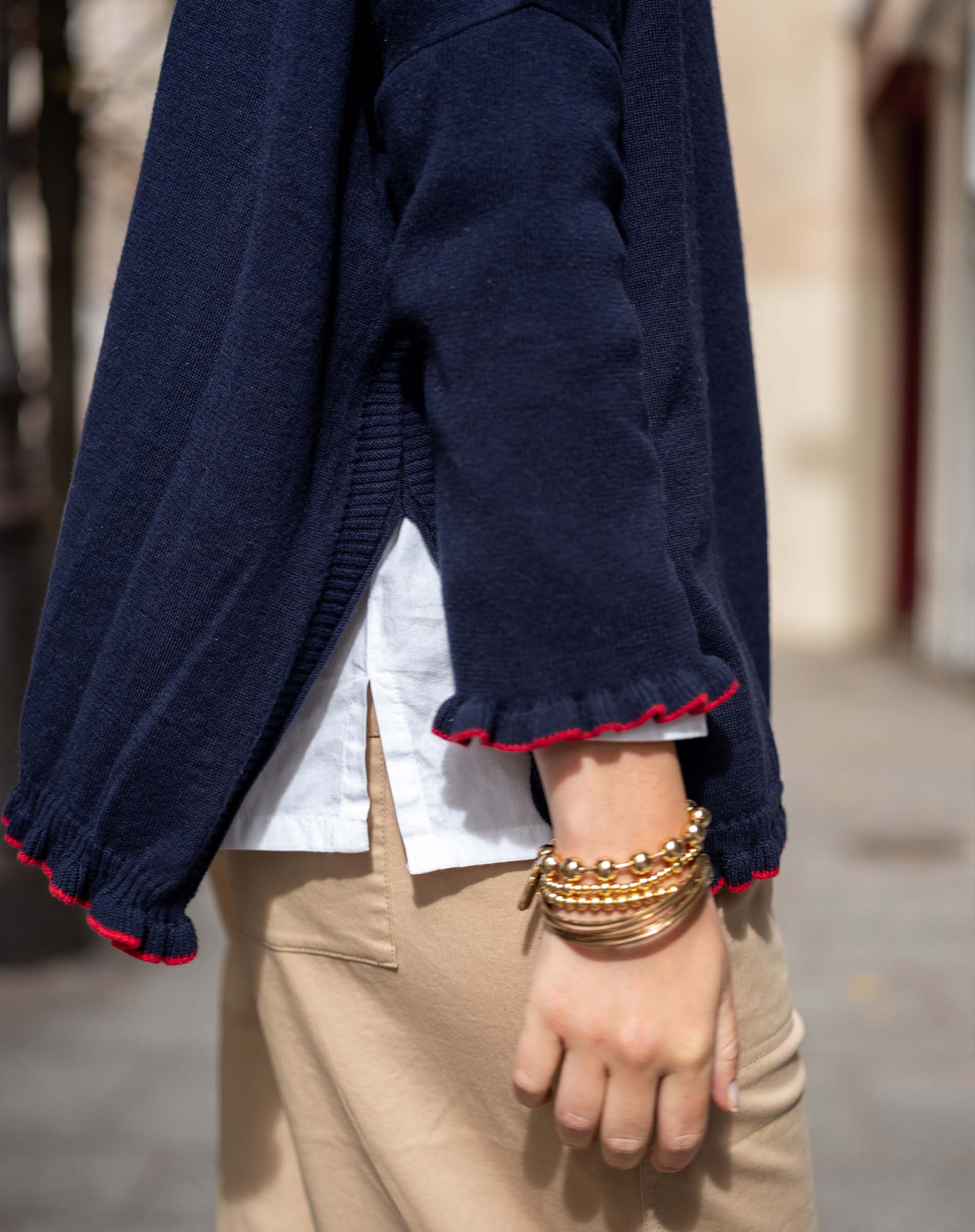 Navy blue sweater with red trim worn by a person, with a blurred background.