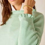 Person wearing a light green sweater with a plain background